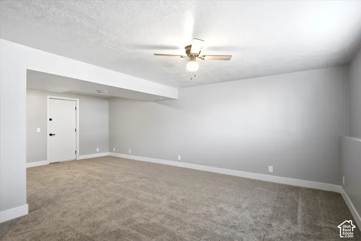 Spacious room with plush carpet flooring, light gray walls, and a ceiling fan with integrated lighting