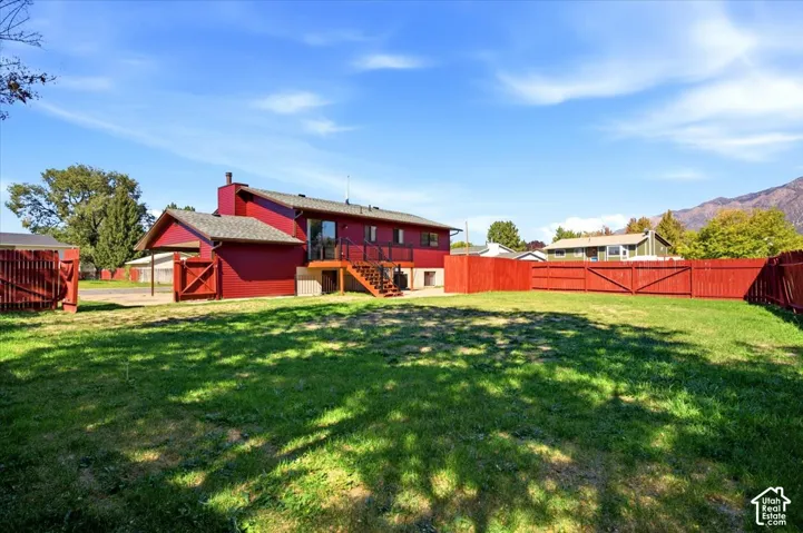 Expansive backyard featuring a manicured lawn, a full wood fence, and a multi-level deck with stairs