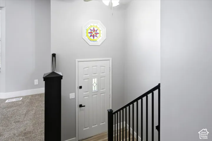 Stained glass decorative octagon window, black metal stair railing, and wood-finish flooring