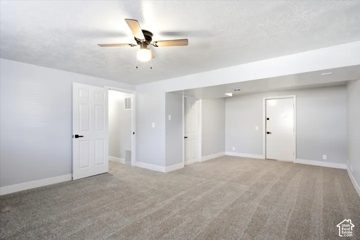 Expansive room featuring plush carpeting, a ceiling fan with integrated lighting, recessed lighting, and multiple paneled doors