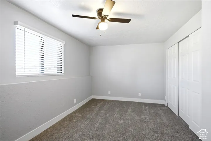 Textured walls with a two-tone paint finish, neutral carpeting, window with blinds, and white bi-fold closet doors