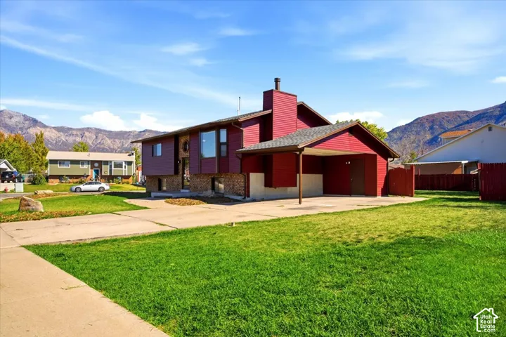 Split-level exterior with red siding, stone accents, and an attached carport