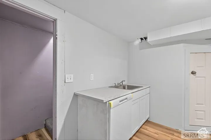 Stainless steel sink with a single-handle faucet, white cabinetry, and a light-toned countertop