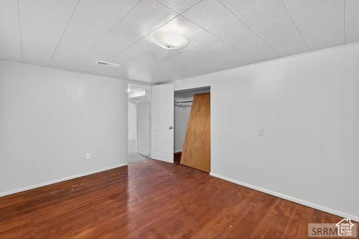 Wood-finish flooring with white wall panels and a white acoustic tile ceiling