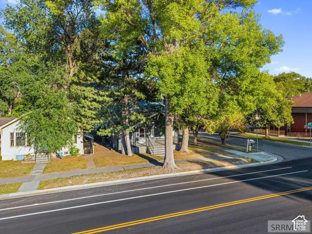Curb appeal featuring mature trees and a paved sidewalk
