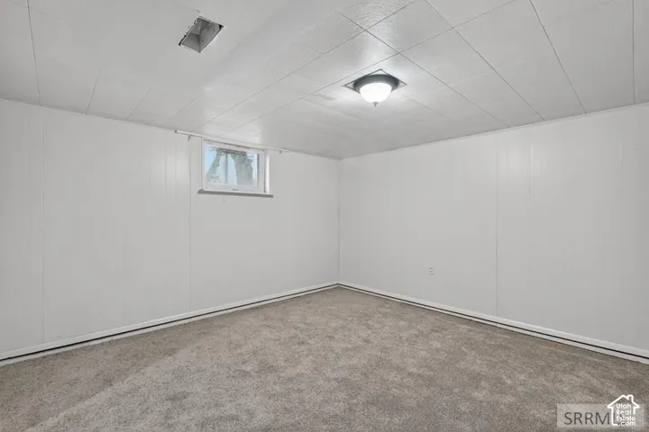 Carpeted room with white paneling and a drop ceiling