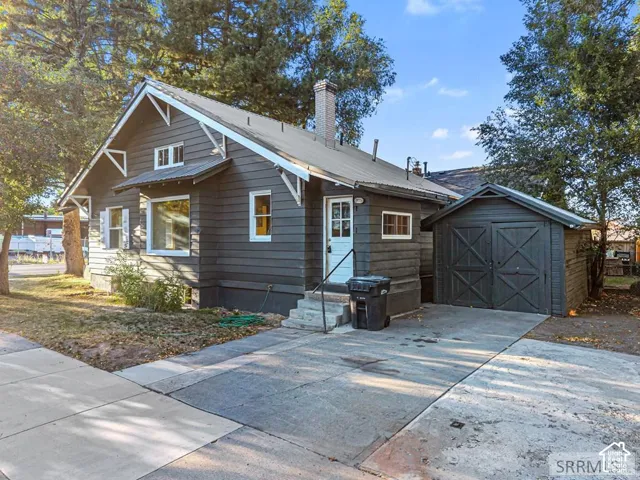 Siding exterior, white trim accents, metal roof, concrete driveway, and detached shed