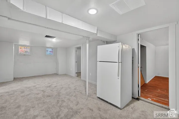 Carpeted interior space with white walls, recessed ceiling lighting, and exposed structural beams