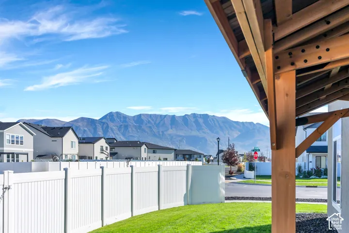 Expansive outdoor space featuring a wood-beam patio structure, manicured lawn, and a white privacy fence