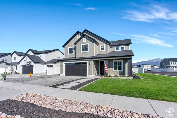 Modern exterior featuring vertical siding, board and batten accents, a dark garage door, and a manicured lawn