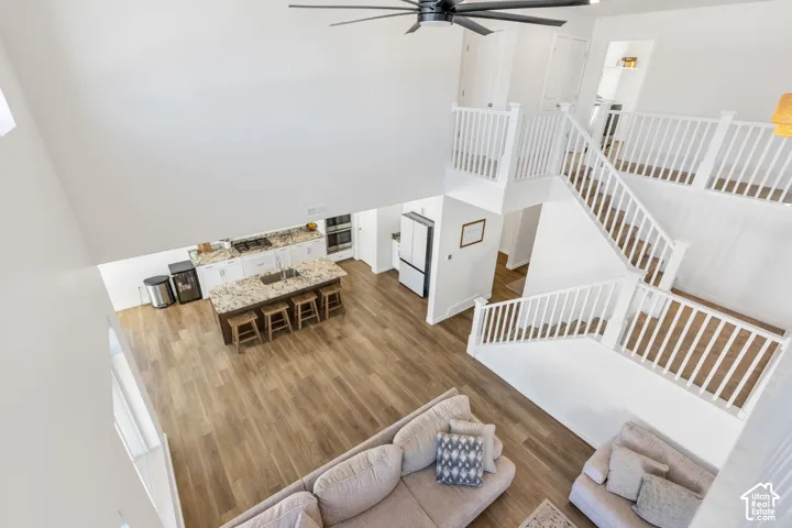 Soaring ceilings, wood-finish flooring, a contemporary ceiling fan, and a multi-level staircase with white balusters