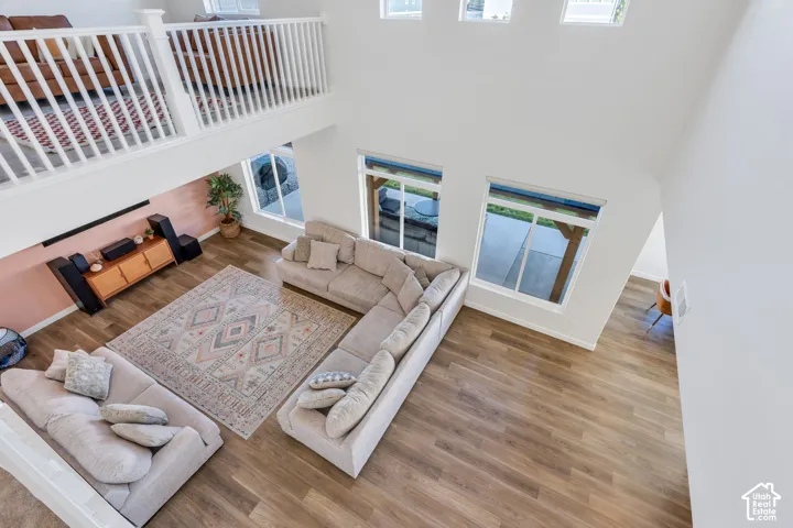 Two-story living area with high ceilings, wood-finish flooring, and multiple windows