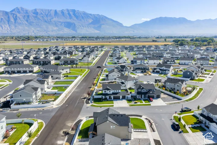 Expansive residential development with a mountain backdrop, featuring single-family homes and townhomes, and a clear road network