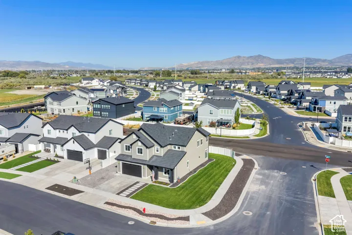 Contemporary residential architecture, well-maintained streets, mountain backdrop, uniform landscaping, clear skies