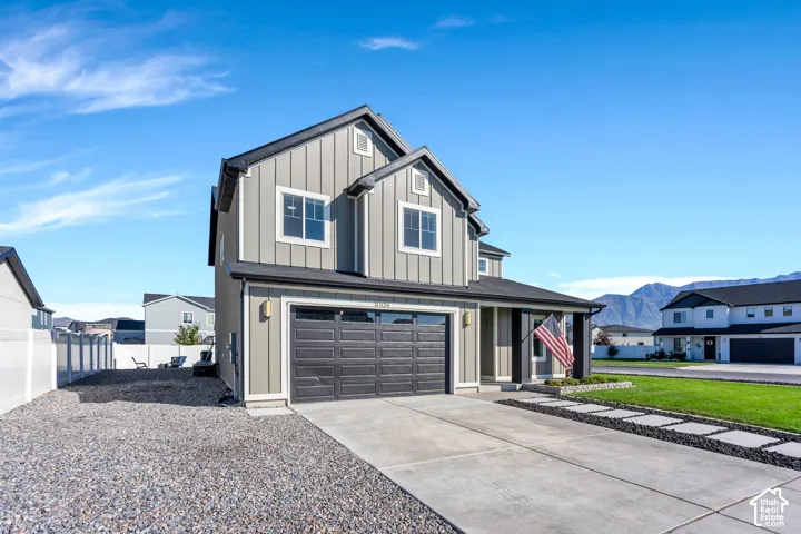 Modern exterior featuring vertical siding, covered entry, attached garage, and concrete driveway with stone accents