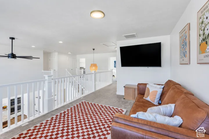 Loft space featuring carpet flooring, white painted railings, a ceiling fan, and recessed lighting