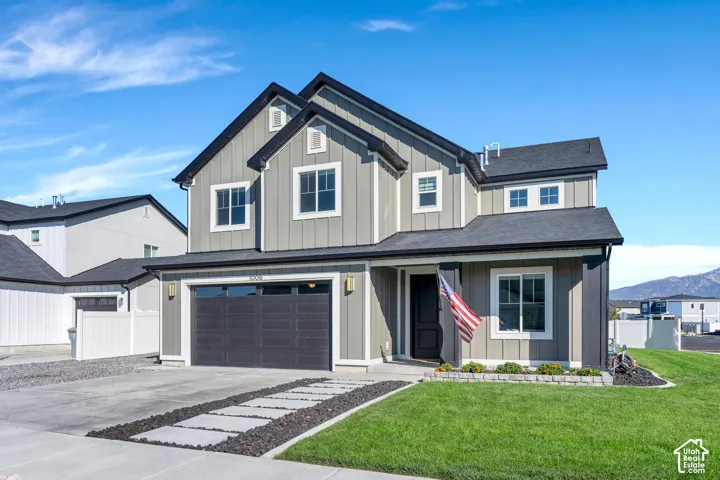 Two-story exterior with board and batten siding, dark shingled roof, two-car garage, and a concrete driveway with decorative stepping stones