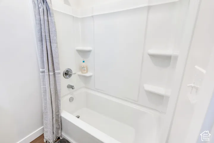 White acrylic tub and shower combination with chrome fixtures and integrated shelving