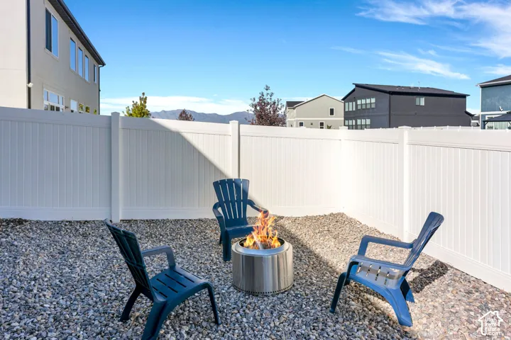 Fenced backyard space featuring gravel ground cover and a fire pit