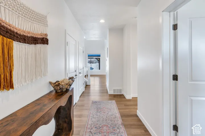 Hallway featuring wood-finish flooring, white paneled doors, and recessed lighting