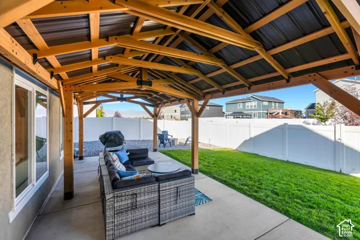 Expansive covered patio with exposed wood beams and a metal roof, concrete patio, and a manicured lawn
