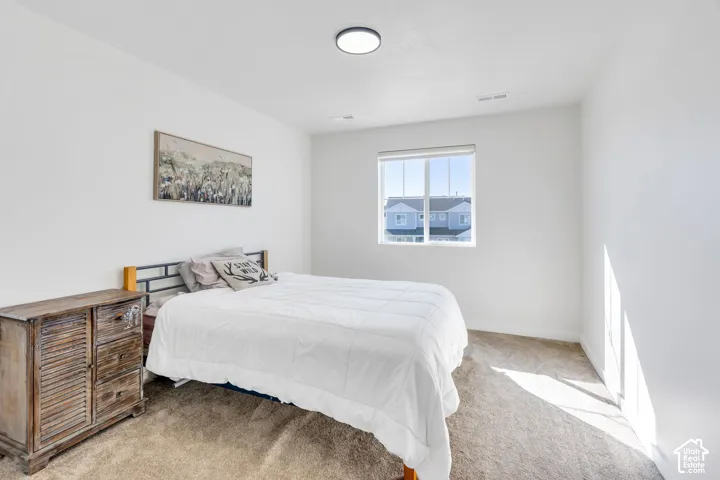 Recessed lighting, large window with roller shade, and plush carpet flooring