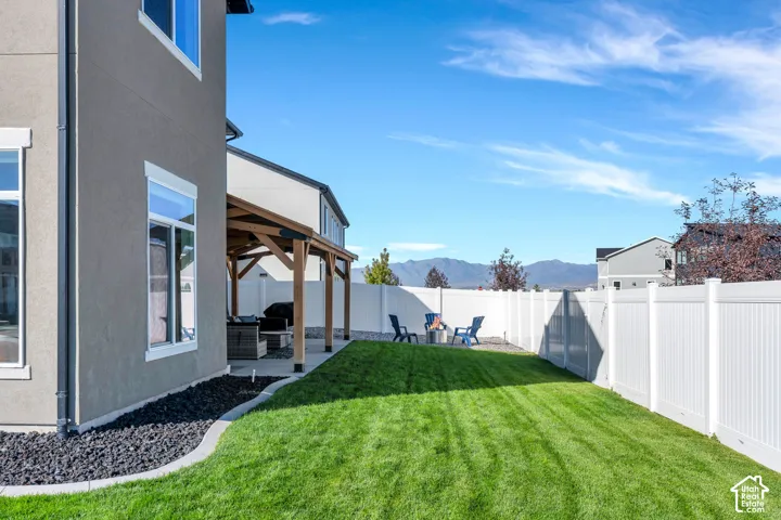 Expansive backyard featuring a manicured lawn, white privacy fencing, and a covered patio with a wood-beam pergola