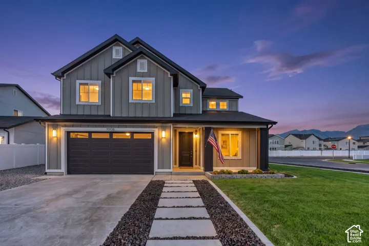 Contemporary farmhouse architectural style featuring board and batten siding, a dark pitched roof, and a two-car garage with a panel door