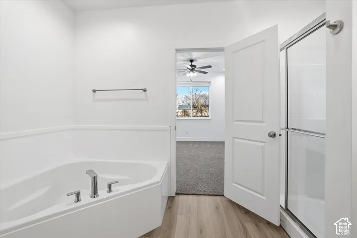 Corner soaking tub with polished chrome fixtures and wood-finish flooring