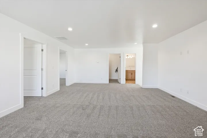Spacious room featuring neutral carpet, white walls, recessed lighting, and white trim