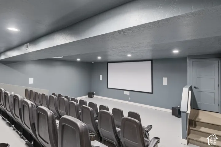 Dedicated home theater with a large projection screen, recessed lighting, and tiered seating