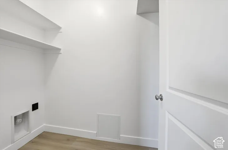 Built-in shelving, wood-finish flooring, and a white paneled door with a brushed nickel knob