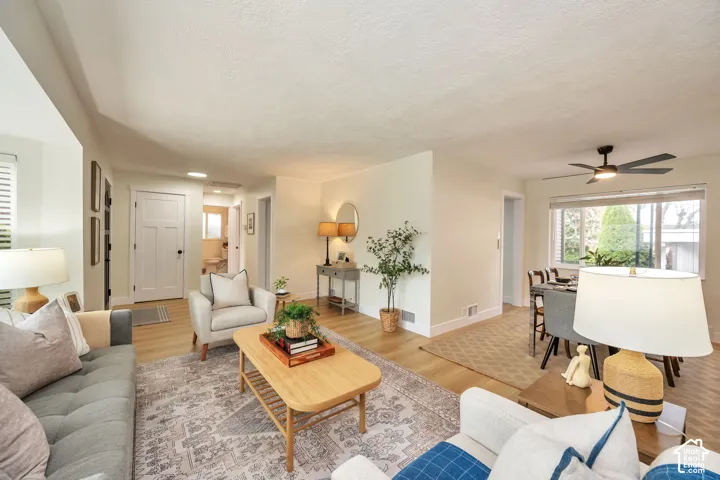 Open-concept living area showcasing hardwood flooring throughout, neutral wall finishes, and abundant natural light from multiple windows
