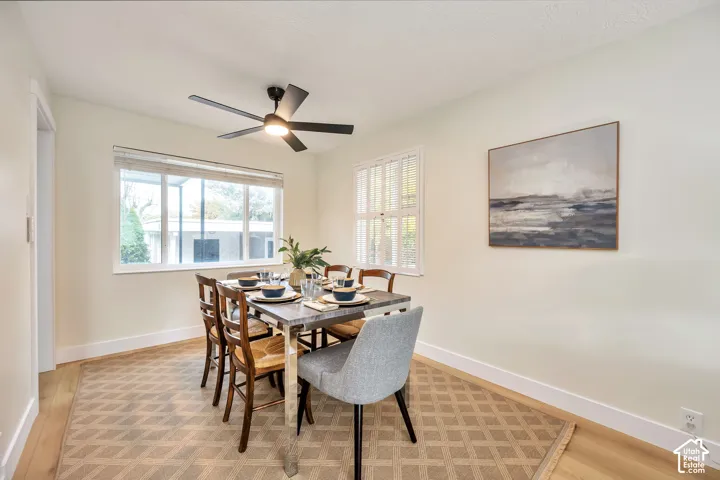 Light-filled dining area featuring wood-finish flooring, a contemporary ceiling fan with integrated lighting, and multiple windows