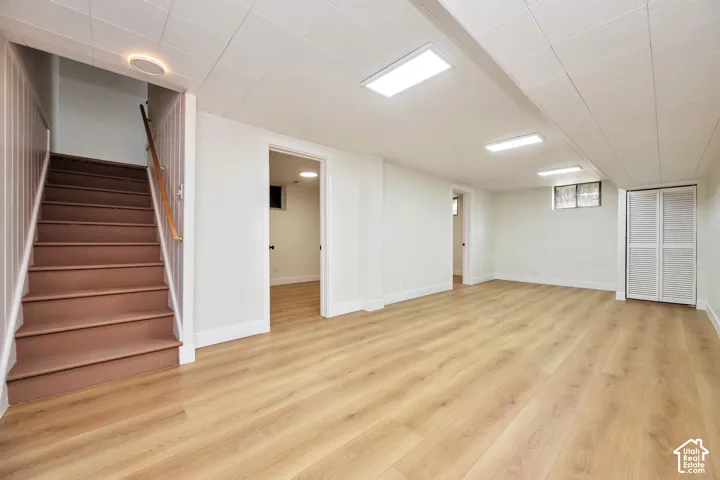 Spacious room featuring wood-finish flooring, recessed lighting, white walls, and a closet with bifold doors