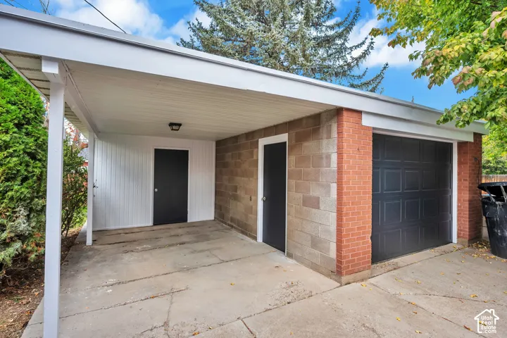 Covered carport with concrete driveway providing convenient vehicle parking, complemented by a brick and stone exterior