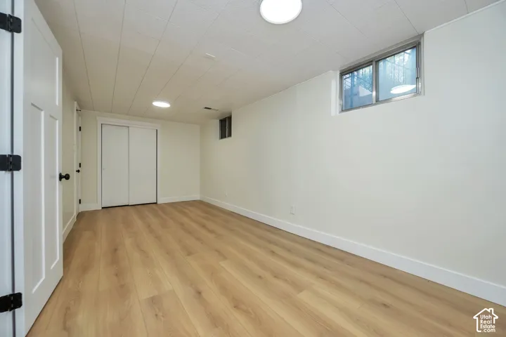 Finished basement featuring warm wood-finish flooring, recessed ceiling lighting, and abundant natural light from transom windows