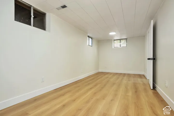 Finished basement featuring wood-finish flooring, recessed ceiling lighting, and multiple windows providing natural illumination