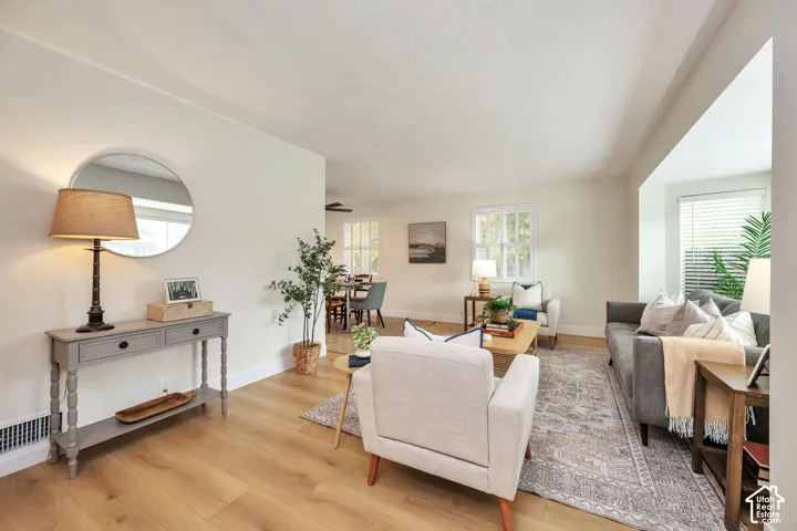 Wood-finish flooring throughout, bright walls, and multiple windows with blinds