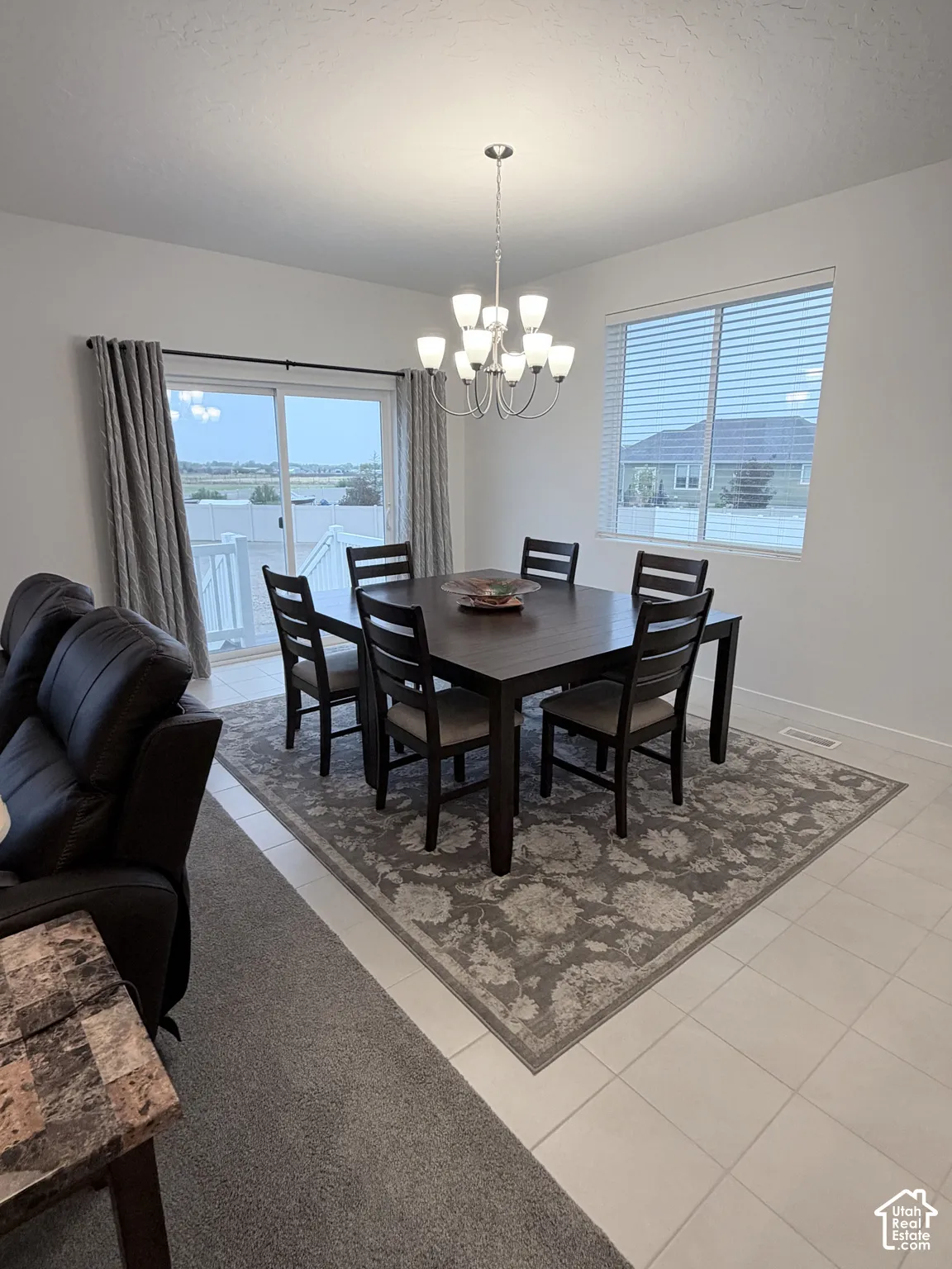 Recessed lighting, tiled flooring, chandelier lighting, sliding glass door, and window with blinds