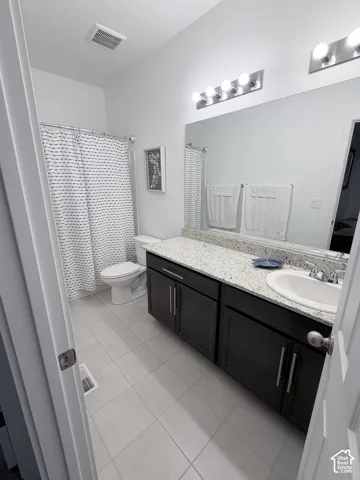 Bathroom featuring a vanity with dark wood-finish cabinetry, a light-toned countertop, an integrated sink, and a framed mirror