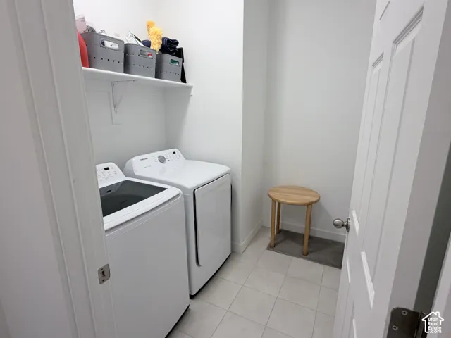 Laundry area with light-colored floor tile, a white wall-mounted shelf, and a white paneled door