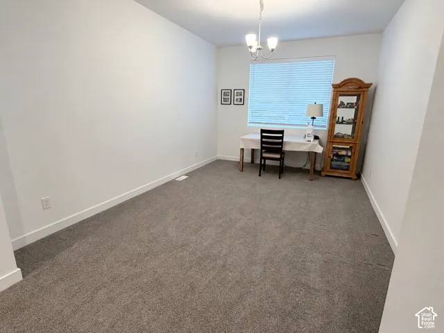 Recessed window with horizontal blinds, overhead chandelier, and neutral wall paint