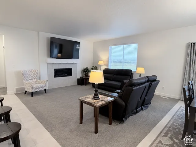 Spacious living area featuring a built-in fireplace with a tiled surround, recessed electric fireplace insert, and a large window providing natural light