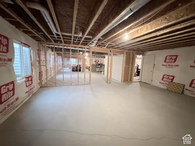 Unfinished basement with exposed ceiling joists, concrete flooring, and framed interior walls