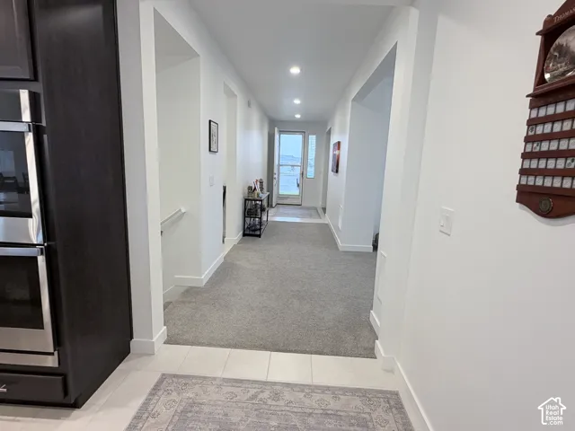 Modern hallway with recessed ceiling lighting, neutral wall finishes, and neutral-toned carpet flooring