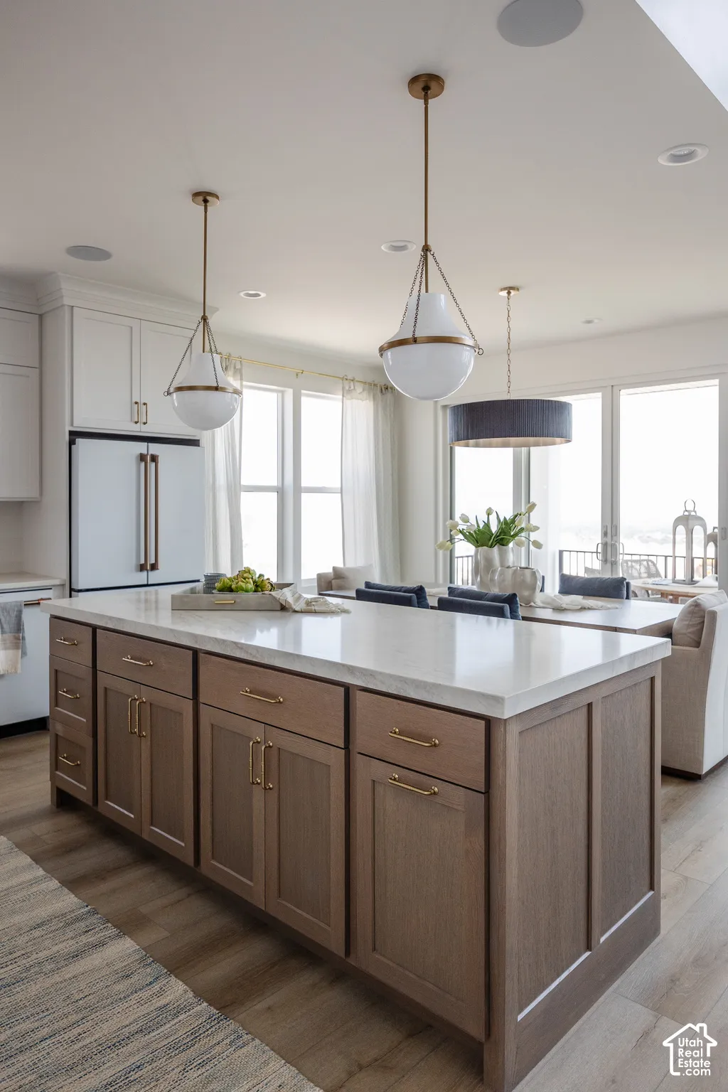 Kitchen island with a light-toned countertop, wood-finish cabinetry, and brass hardware