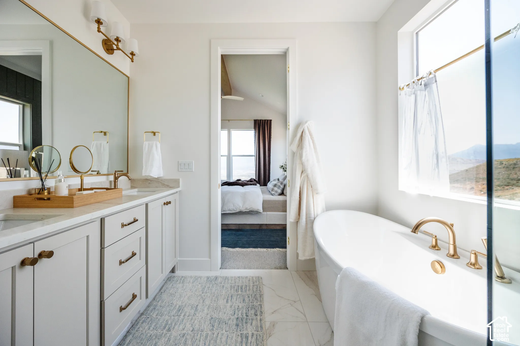 Dual vanity with integrated sinks, white cabinetry, and brass hardware