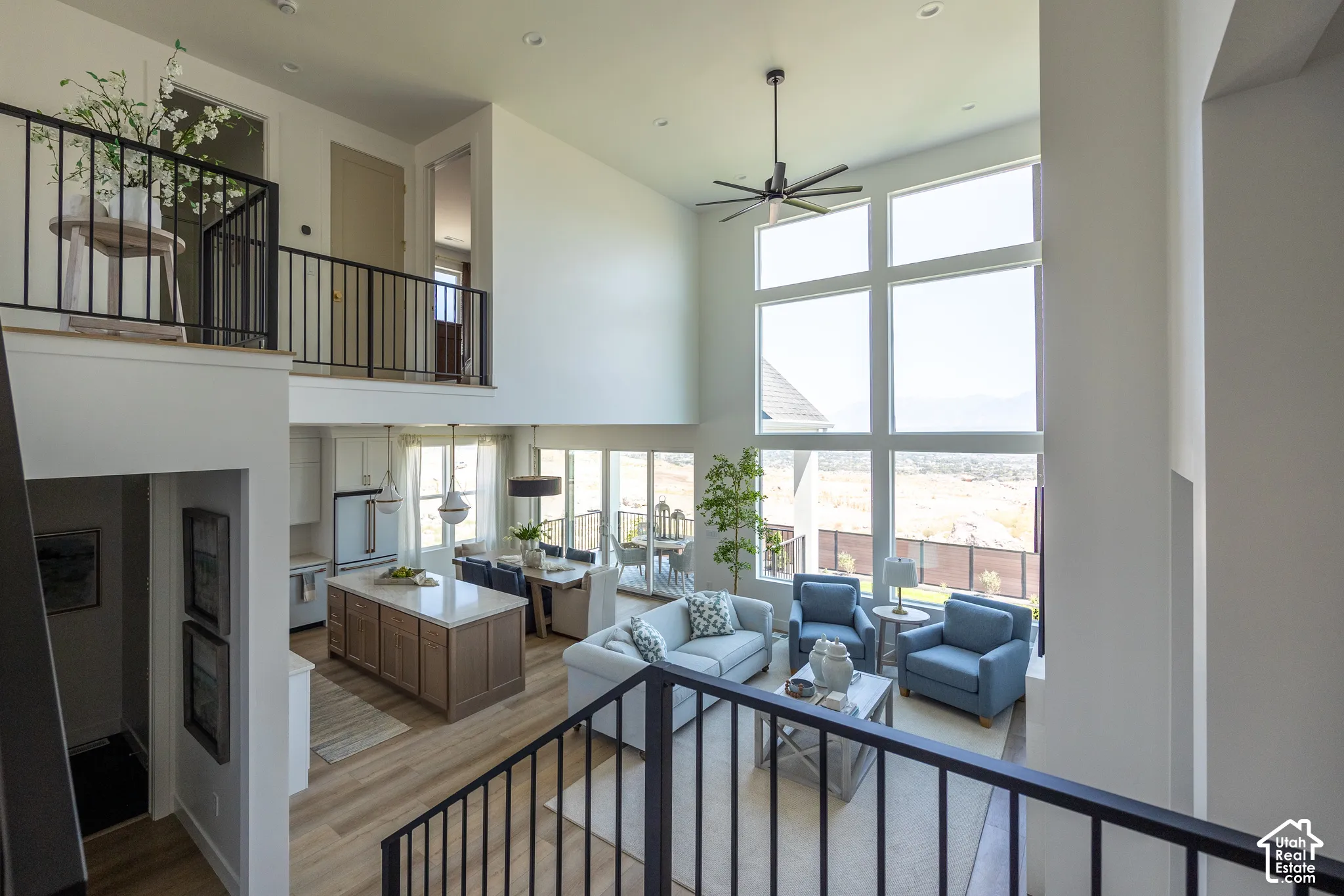 Two-story living area with expansive floor-to-ceiling windows, soaring ceilings, and wood-finish flooring