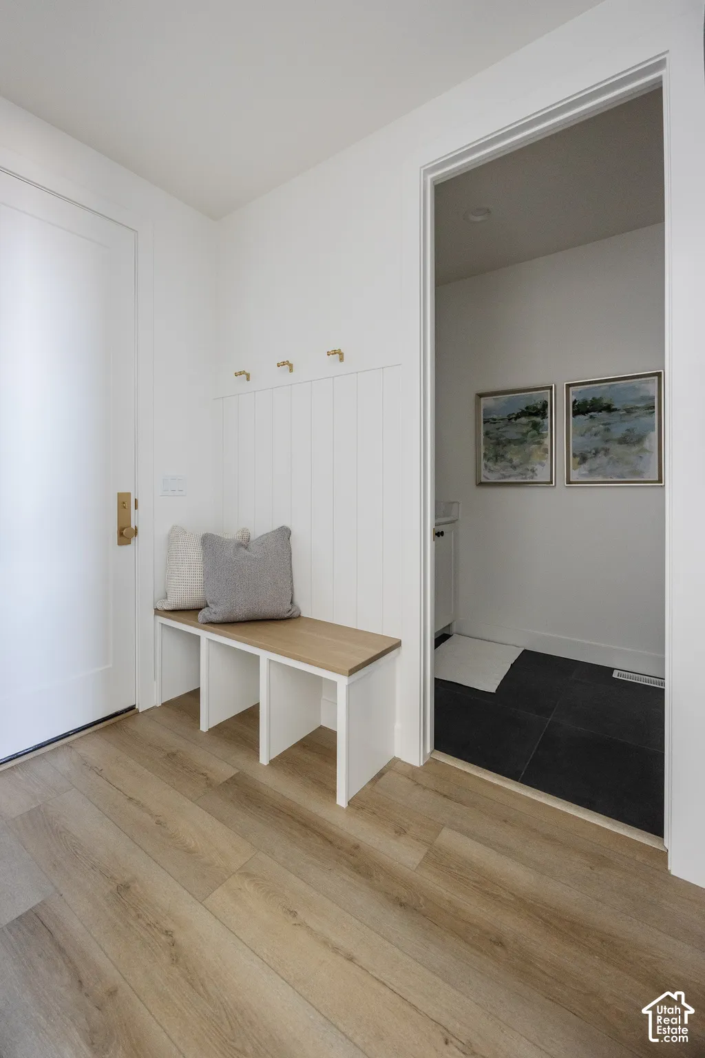 Entryway featuring wood-finish flooring, a built-in bench with a wood-finish top, and wall-mounted hooks